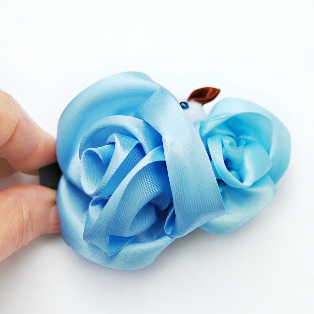 two blue roses hair clip in a hand