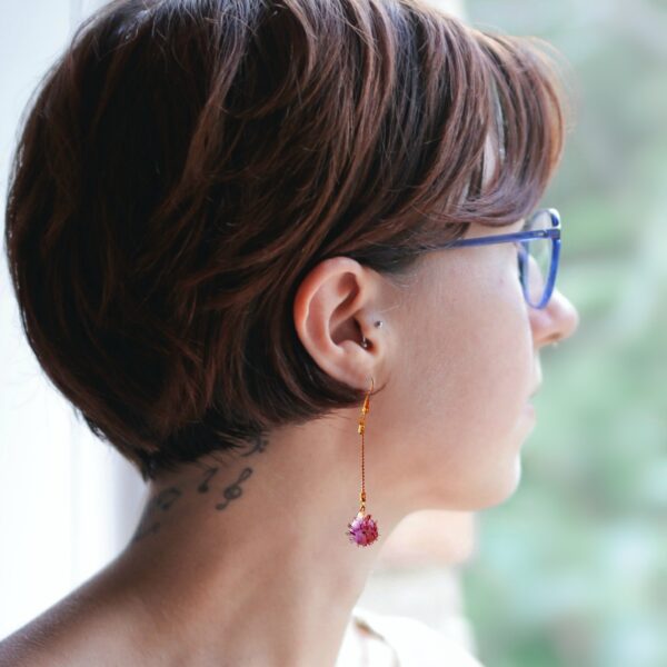 a woman wearing pompom dangle earrings