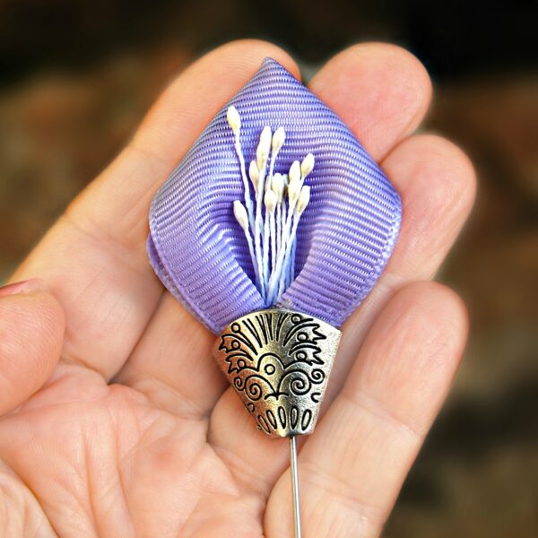 A hand holding a purple lapel pin