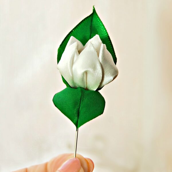 a hand holding flower lapel pin