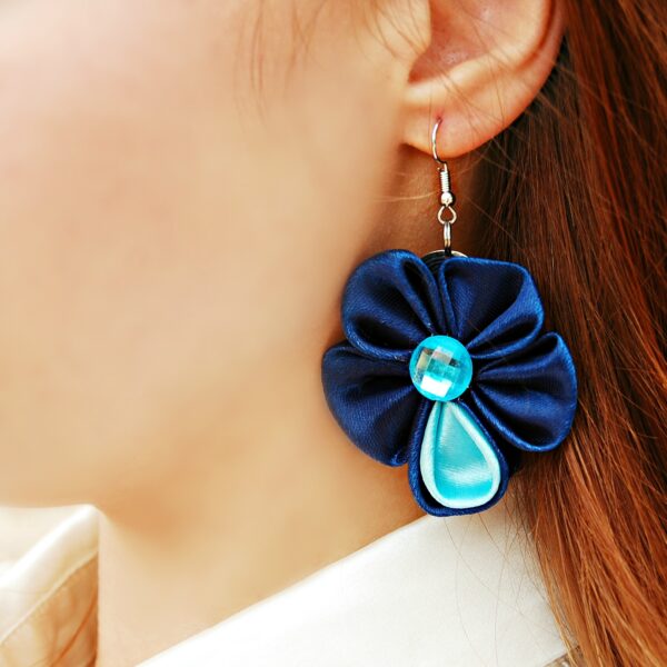 a woman wearing blue flower earrings