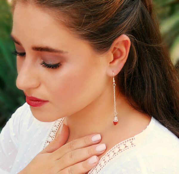 a woman wearing red crystal dangle earrings