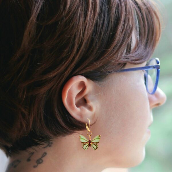 a woman wearing seafoam butterfly earrings