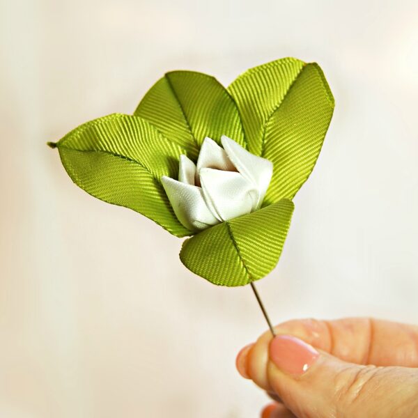 holding lily men's lapel pin in a hand