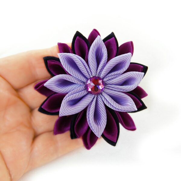 purple flower lapel pin in a hand