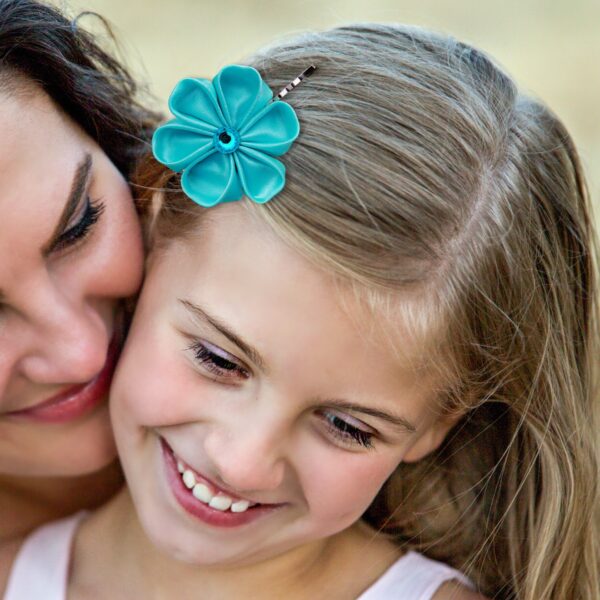 a girl wearing teal flower bobby pin