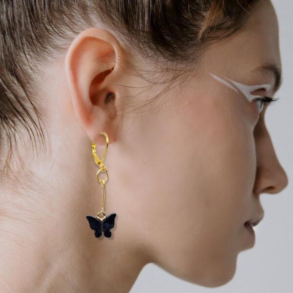 A woman wearing black dangle butterfly earrings